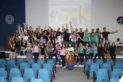 Grupo de estudantes em um salão de eventos comemorando a apresentação